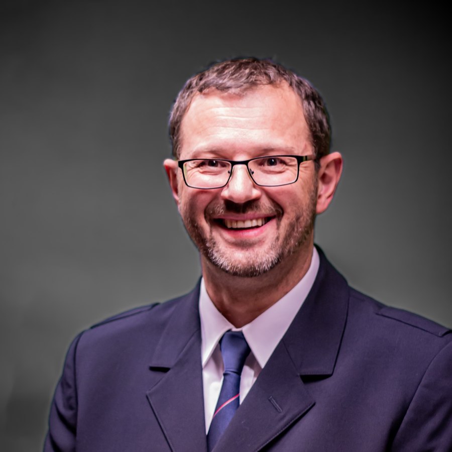 Porträt von Martin Spohner im dunklen Sakko mit Krawatte, lächelnd